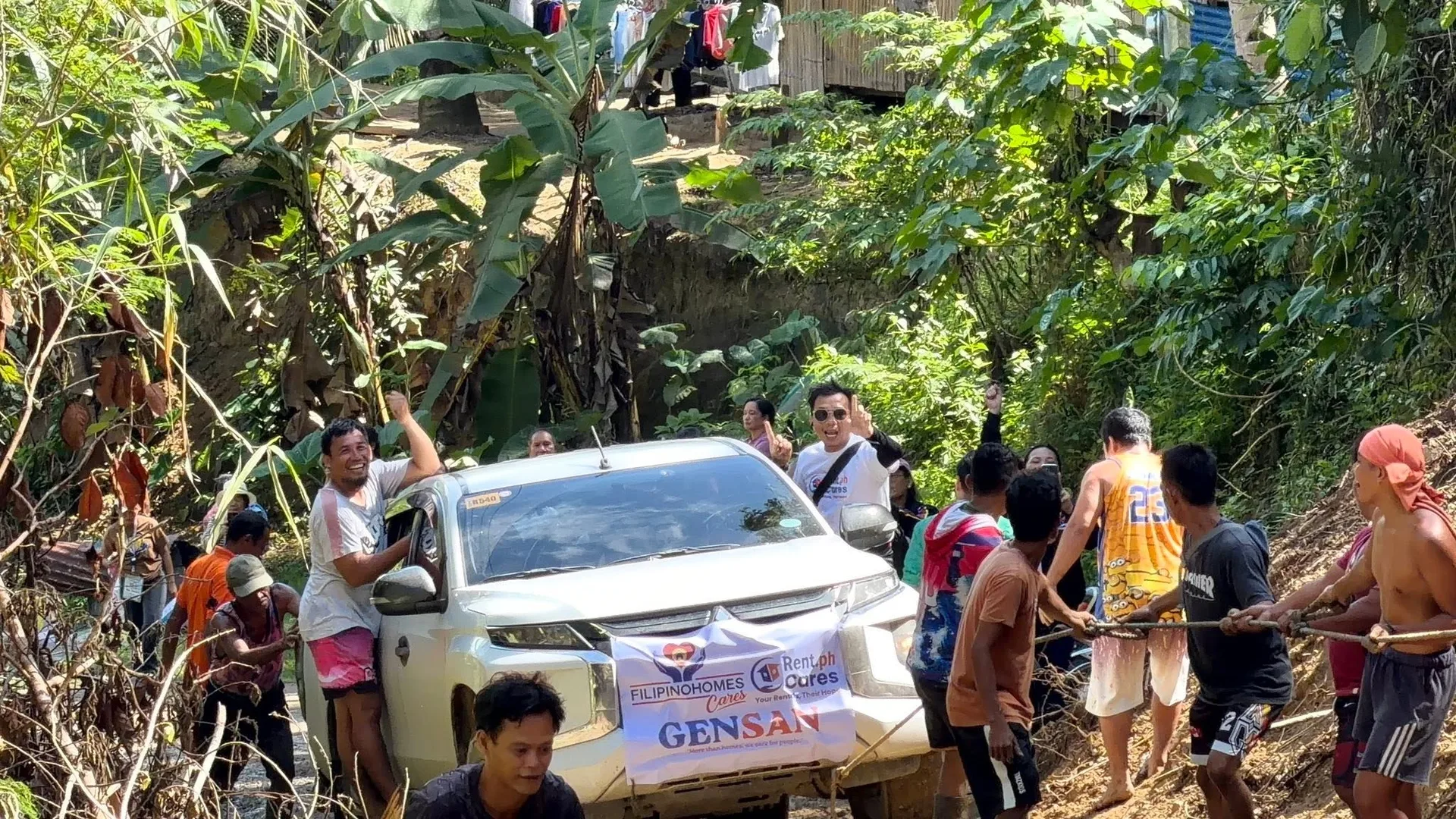 Volunteers and community members pulling a relief vehicle through rugged terrain
